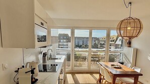 Una cocina moderna con un ventanal grande, un comedor con mesa de madera y vistas a la ciudad.