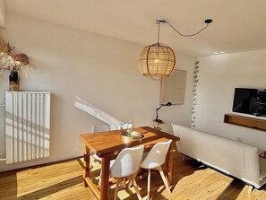 Een eetgedeelte met een houten tafel en witte stoelen, een hanglamp en een radiator.