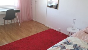 A bedroom with a bed, a desk, a chair, a small table, and a window with curtains. - Room-cozy Guest Room in Green Uppsala - (Uppsala)