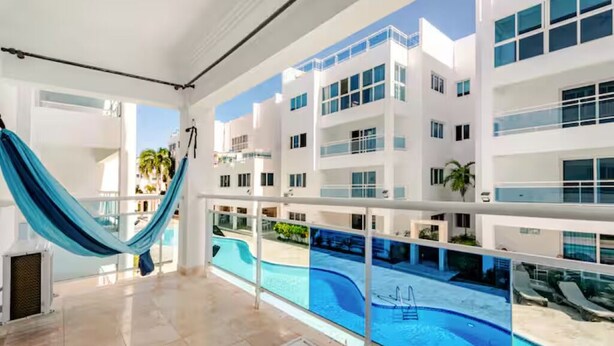 Ett modernt hotell med en swimmingpool, en hängmatta och utsikt över poolområdet.