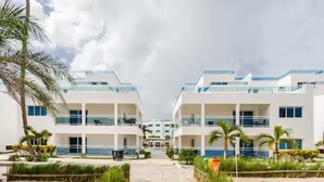 Ett modernt hotell med en central innergård, flera balkonger och palmer.