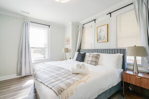 A hotel room with a large bed, two bedside tables, a window with curtains, and a wall-mounted artwork. - Spacious 3BR/3BA | Sleeps 7 | 10 Min to Stadium (Philadelphia)