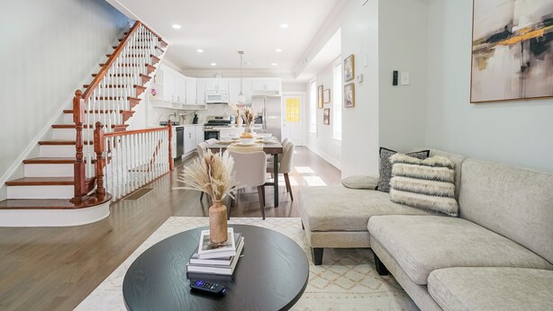 A modern living room with a staircase, a dining area, and a kitchen. - Spacious 3BR/3BA - Sleeps 7 - 10 Min to Stadium (Philadelphia)
