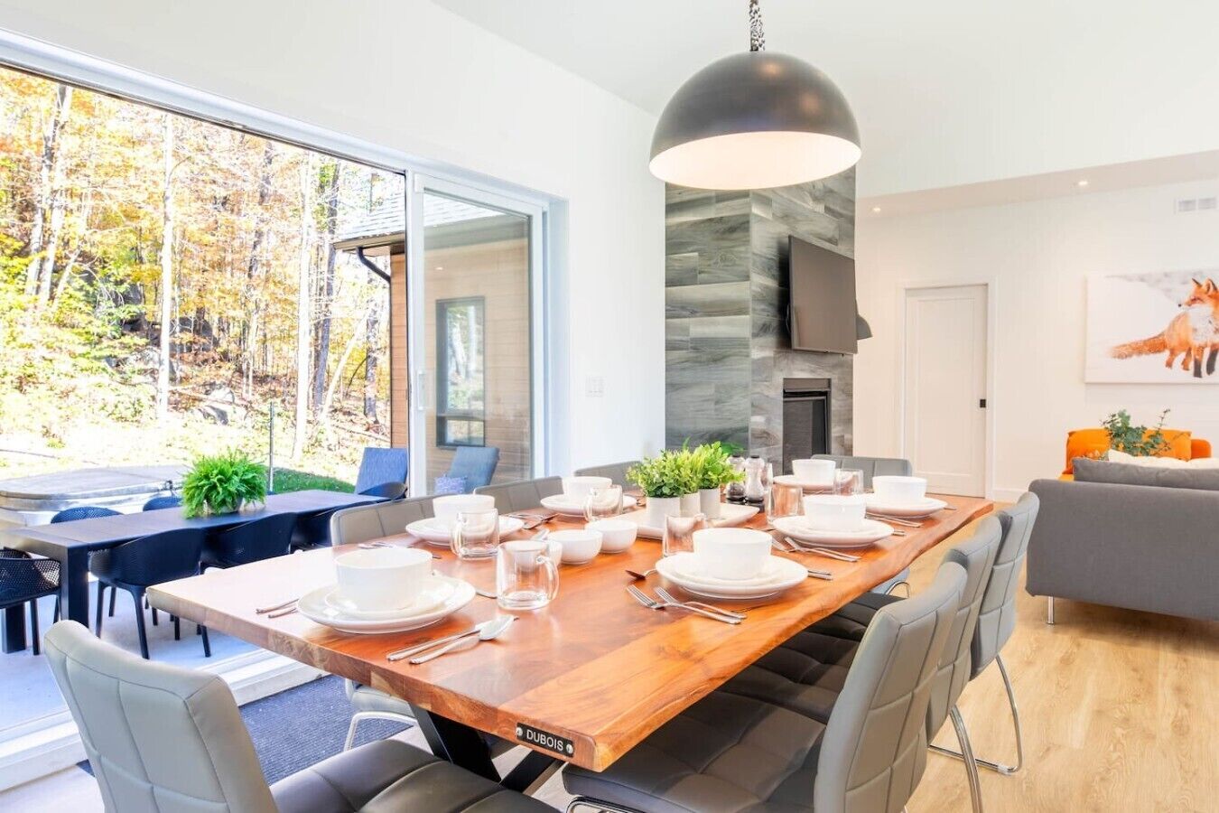 A modern dining area with a large wooden table set for a meal, surrounded by comfortable seating.