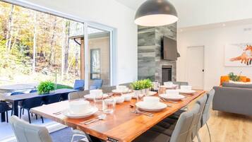 A modern dining area with a large wooden table set for a meal, surrounded by comfortable seating.
