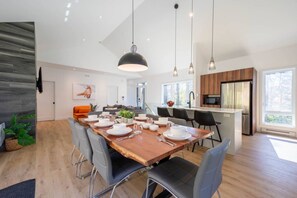 Une cuisine moderne dotée d’un îlot central, un coin repas avec une table en bois et un espace de vie comprenant un canapé et un tableau.