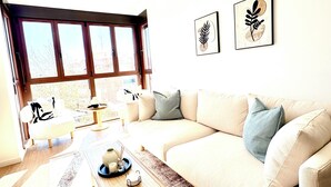 A living room with a sofa, coffee table, and artwork on the wall. - New Modern Retreat at Malvarrosa Beach (València)