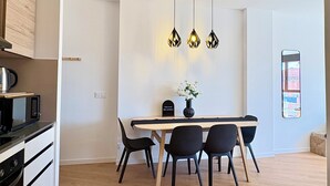 A modern kitchen with a microwave, stove, and dining area with a table and chairs. - New Modern Retreat at Malvarrosa Beach (València)