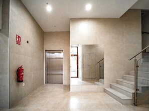 Ein modernes Interieur mit einem an der Wand montierten Feuerlöscher, einer Tür und einer Treppe mit Glastrennstäben.