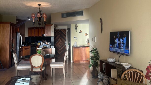 A spacious living room with a dining area, kitchen, and a TV mounted on the wall. - Room-mediterranean Caribbean View Villag (Humacao)