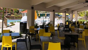 An outdoor dining area with yellow and black chairs, tables, and a ceiling fan. - Room-mediterranean Caribbean View Villag (Humacao)