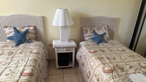 A room with two beds, each with a starfish pillow, a nightstand with a lamp, and a small basket. - Room-mediterranean Caribbean View Villag (Humacao)