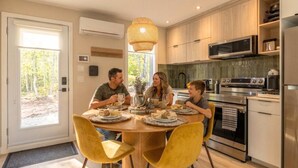 A modern kitchen with a dining table, chairs, and a large window. - Écohaven-Spa, nature & feu sous les étoiles (Brownsburg)
