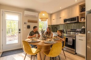 A modern kitchen with a dining table, chairs, and a large window. - Écohaven-Spa, nature & feu sous les étoiles (Brownsburg)