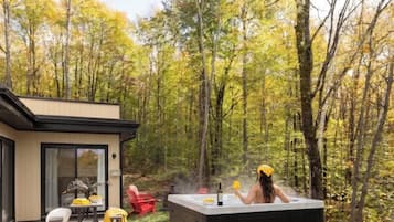 A hot tub in a forested area with a house in the background.