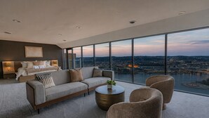 A modern living room with a large sofa, a coffee table, and a view of a cityscape and river. - Luxury Living | Skyline Views | Grandview Retreat (Pittsburgh)