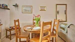 A dining area with a round wooden table, four wooden chairs, a vase of tulips, and two framed pictures on the wall. - Host & Stay | Nile Street Retreat (Norwich)