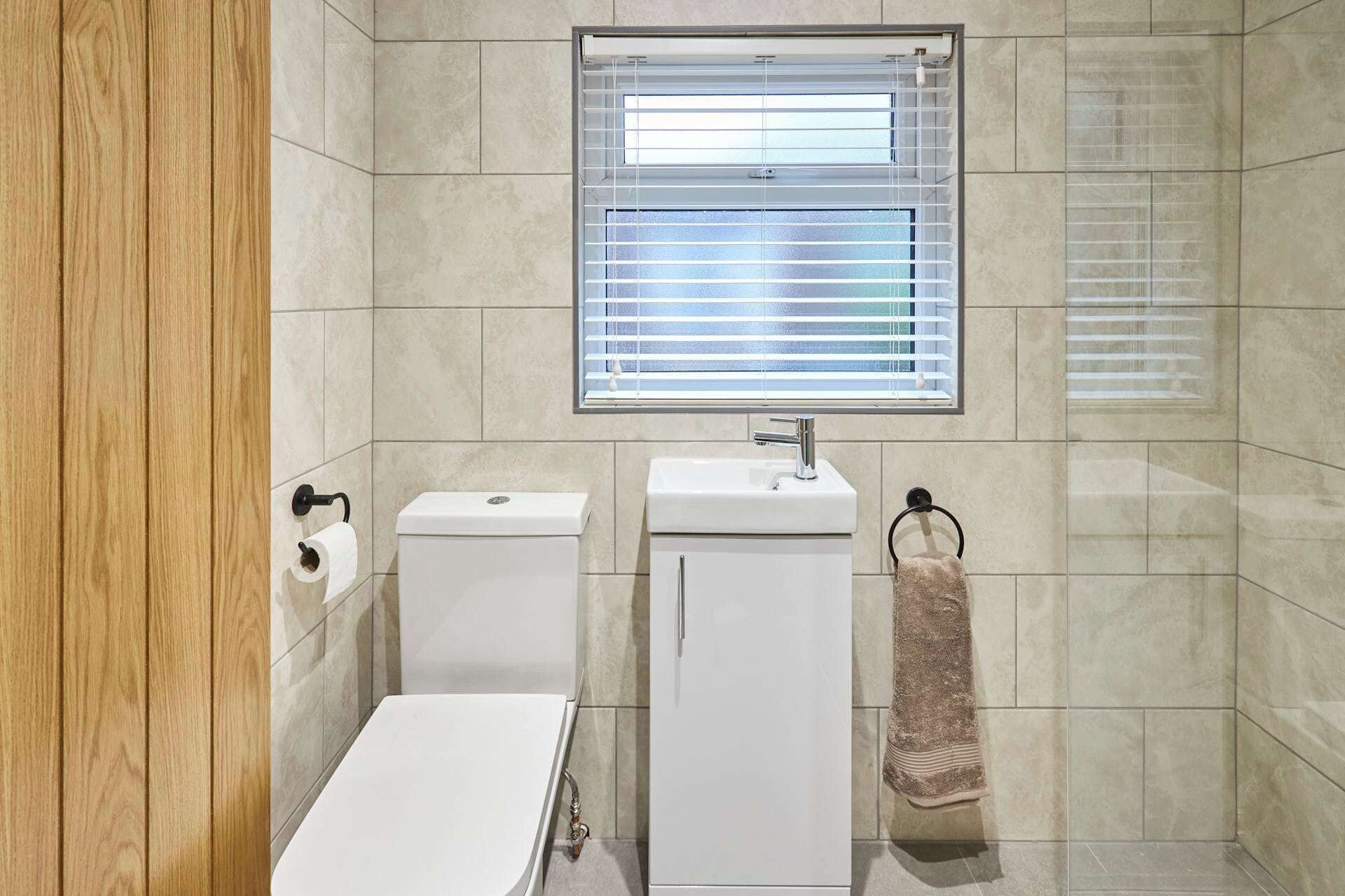 A bathroom with a toilet, sink, and window.