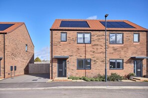 A two-story brick building with solar panels, a gated driveway, and a clear blue sky. - Host & Stay | Abbey View House (Whitby)