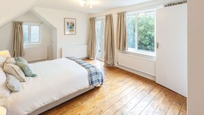 Un dormitorio con cama, radiador, ventana y puerta.