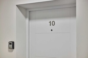 A door with the number 10, a doorbell, and a small rectangular object on the wall. - Host & Stay | 10 Queens Court (Merseyside)