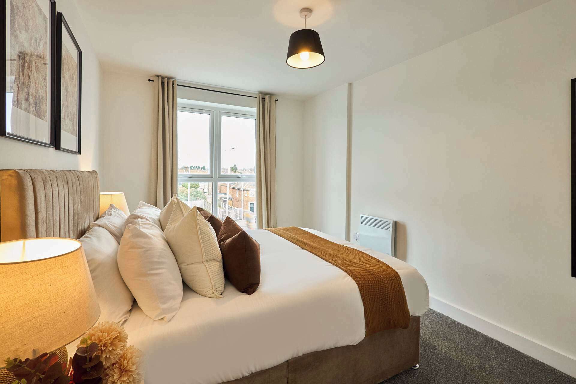 Une chambre d’hôtel avec un lit, une lampe, une fenêtre et un luminaire au plafond.