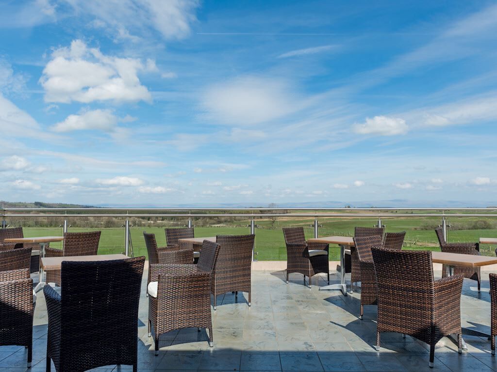 Eine Terrassengruppe mit Korbmöbeln und Blick auf die Landschaft.