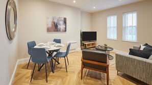 Ett modernt vardagsrum med en matplats, en platt-TV och en soffa.