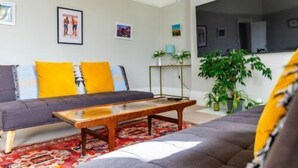 Ein Wohnzimmer mit einer Couch, einem Couchtisch und einer großen Kübelpflanze.