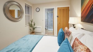 Ein Schlafzimmer mit einem Bett, einem runden Spiegel, einer Uhr, einer Tür und einer Dusche.