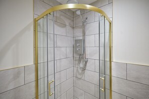 A shower enclosure with a curved glass door, a handheld showerhead, and a wall-mounted control panel. - Host & Stay | Studio @ Temperance House (Saltburn-By-The-Sea)
