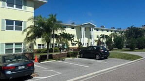 A building with a parking lot, two cars, and palm trees. - 2 BR 2 BA Condo  (Cape Canaveral)