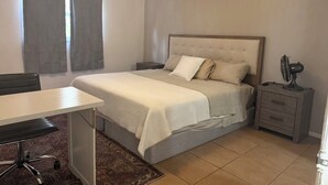 A bedroom with a bed, bedside table, chair, and a small desk. - 2 BR 2 BA Condo  (Cape Canaveral)