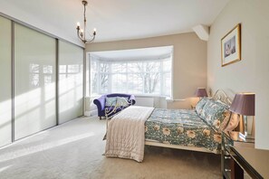 Une chambre à coucher avec un lit, une fenêtre, une chaise et un lustre.
