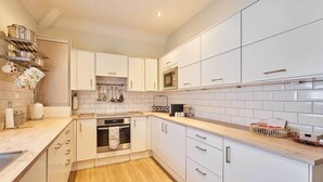 Une cuisine moderne avec des armoires blanches, des appareils en acier inoxydable et un plan de travail en bois.