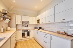 Une cuisine moderne avec des armoires blanches, des appareils en acier inoxydable et un plan de travail en bois.