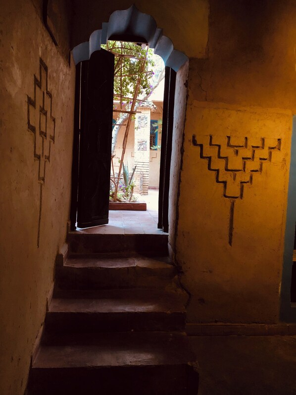 Una escalera estrecha con un diseño decorativo en la pared, que conduce a un vano abierto.
