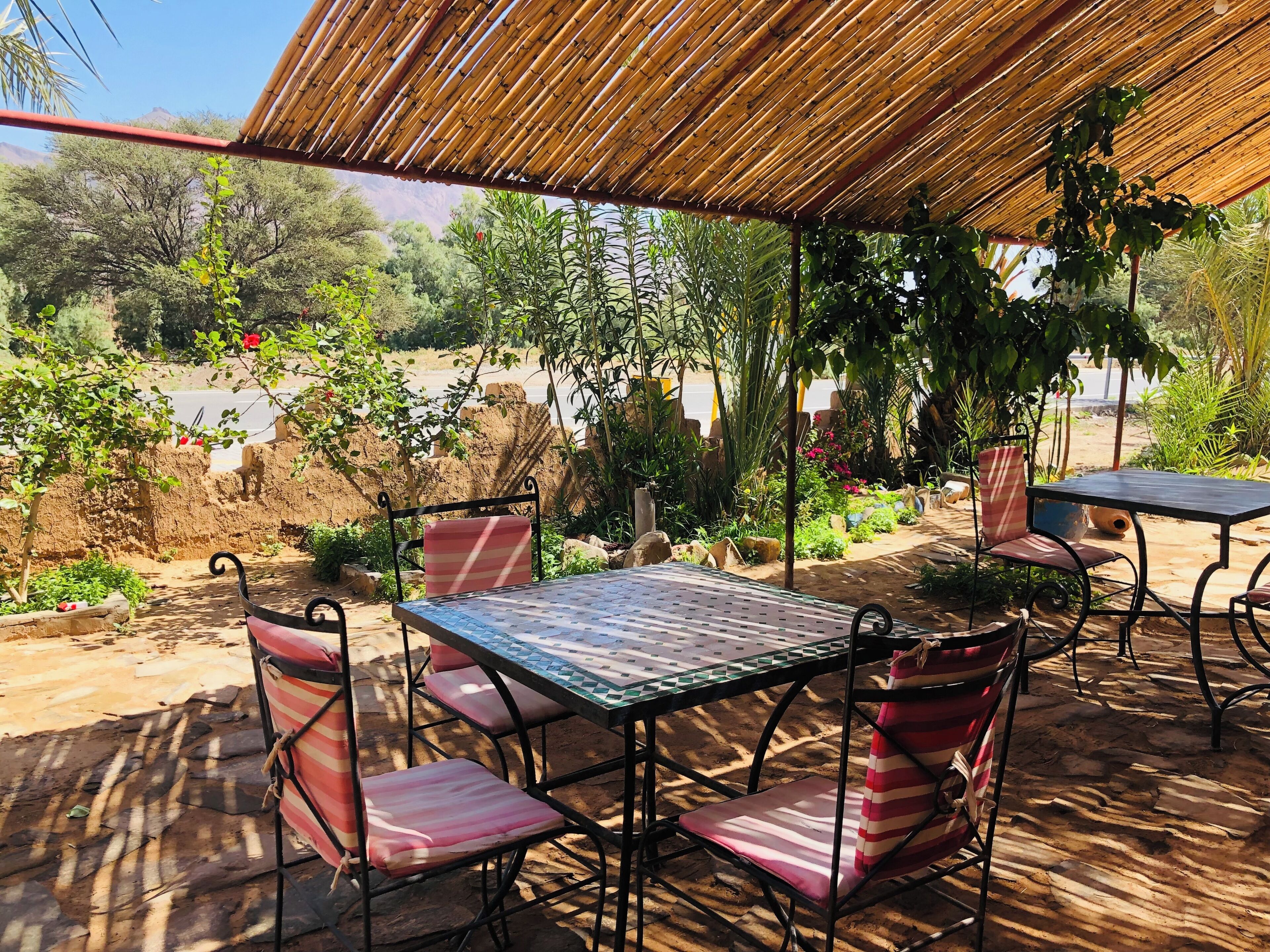 An outdoor seating area with a table and chairs, surrounded by plants and a view of the landscape.