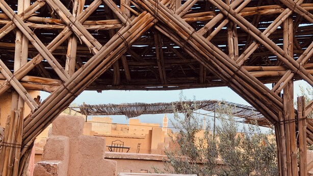 A traditional structure with a bamboo framework, a thatched roof, and a view of surrounding buildings. - Kasbah berbère Ouriz (Tansifte)