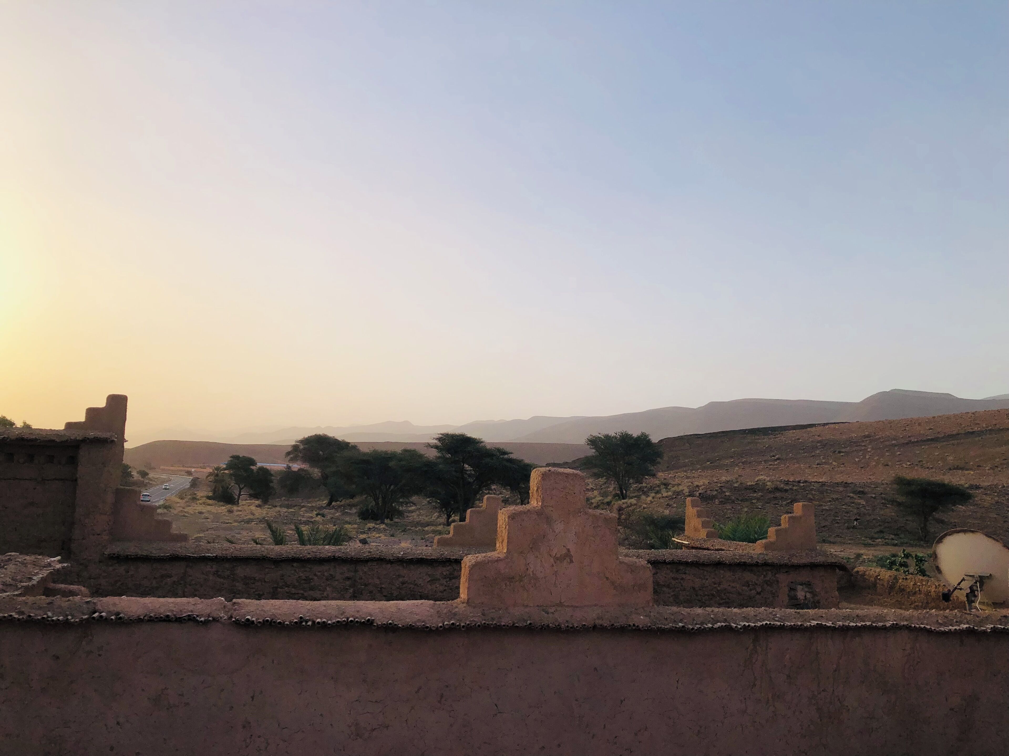 A desert landscape with ancient ruins and a road in the distance.