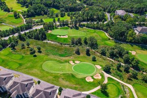 An aerial view of a golf course with multiple greens, sand bunkers, and a residential area with houses. - GOLF VIEWS - Spacious 3BR Condo with Loft & Pool (Branson)