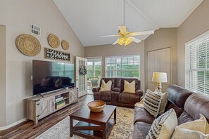 A living room with a television, leather sofas, a wooden coffee table, and a ceiling fan. - GOLF VIEWS - Spacious 3BR Condo with Loft & Pool (Branson)