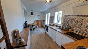 Una cocina moderna con suelo de madera, zona de comedor con mesa y sillas, cafetera y salpicadero decorativo.