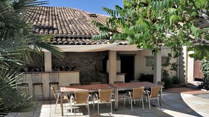 Un patio con mesa y sillas, un muro de piedra y un techo de baldosas.
