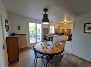 Une cuisine avec une table ronde en bois, un meuble en bois et une fenêtre donnant sur un patio.