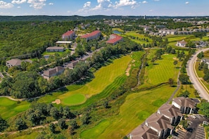 An aerial view of a residential area with multiple buildings, green lawns, and a golf course. - Spacious 2BR Condo - GOLF VIEWS - Pool & Dog OK (Branson)
