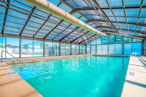 An indoor swimming pool with clear blue water, a roofed structure, and a view of the outside. - Warm 1BR Condo - FIREPLACE & POOL - Branson (Branson)