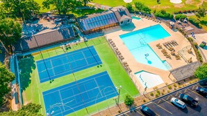 An aerial view of a property with two tennis courts, a swimming pool, and a parking lot. - Pointe Royale - 1BR/1B - pools and fitness center (Branson)