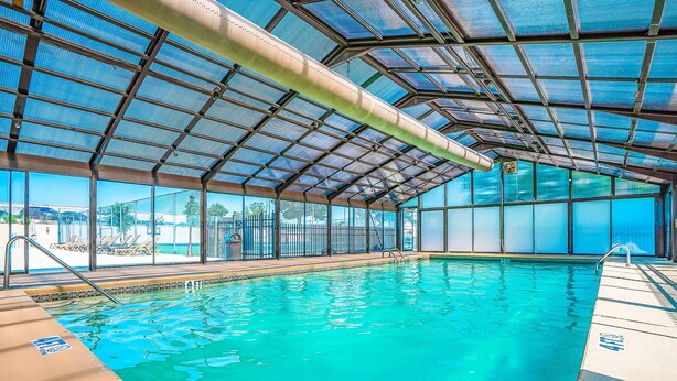 An indoor swimming pool with clear blue water, a covered roof, and a view of the outside. - Pointe Royale - 1BR/1B - pools and fitness center (Branson)