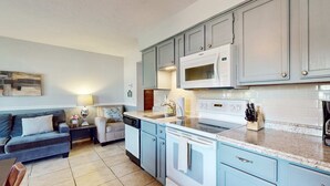 Une cuisine de taille réduite avec des meubles bleu clair, un four à micro-ondes blanc et une cuisinière.